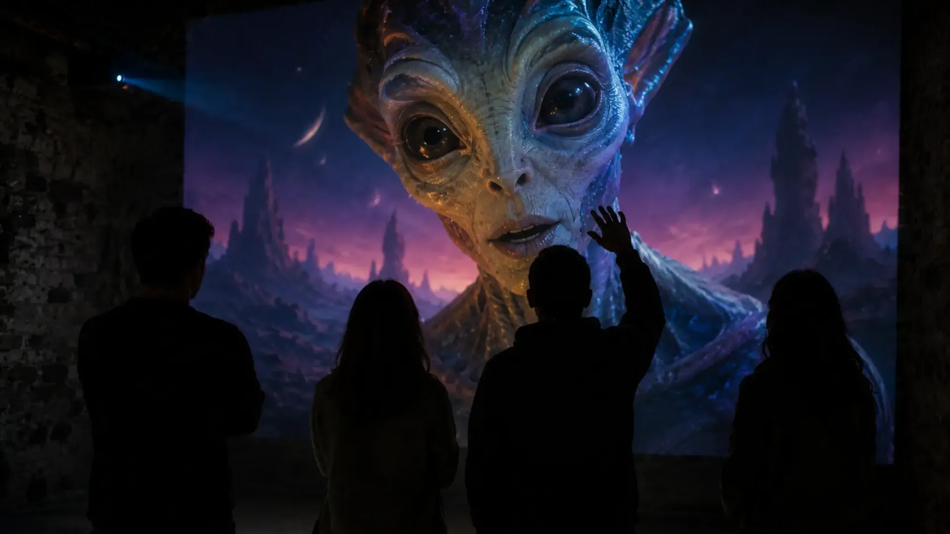 Groupe de visiteurs silhouettés devant une projection murale d'une créature extraterrestre parlant, dans une salle immersive